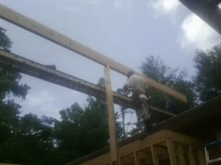Carpenter setting a ridge beam over a new addition frame — Ice Dam Removal by Roofing Brothers in Derry