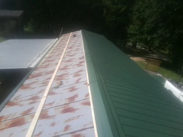 Old rusted panels beside newly installed green metal roofing — Wind Damage Roof Repair by Roofing Brothers in Derry
