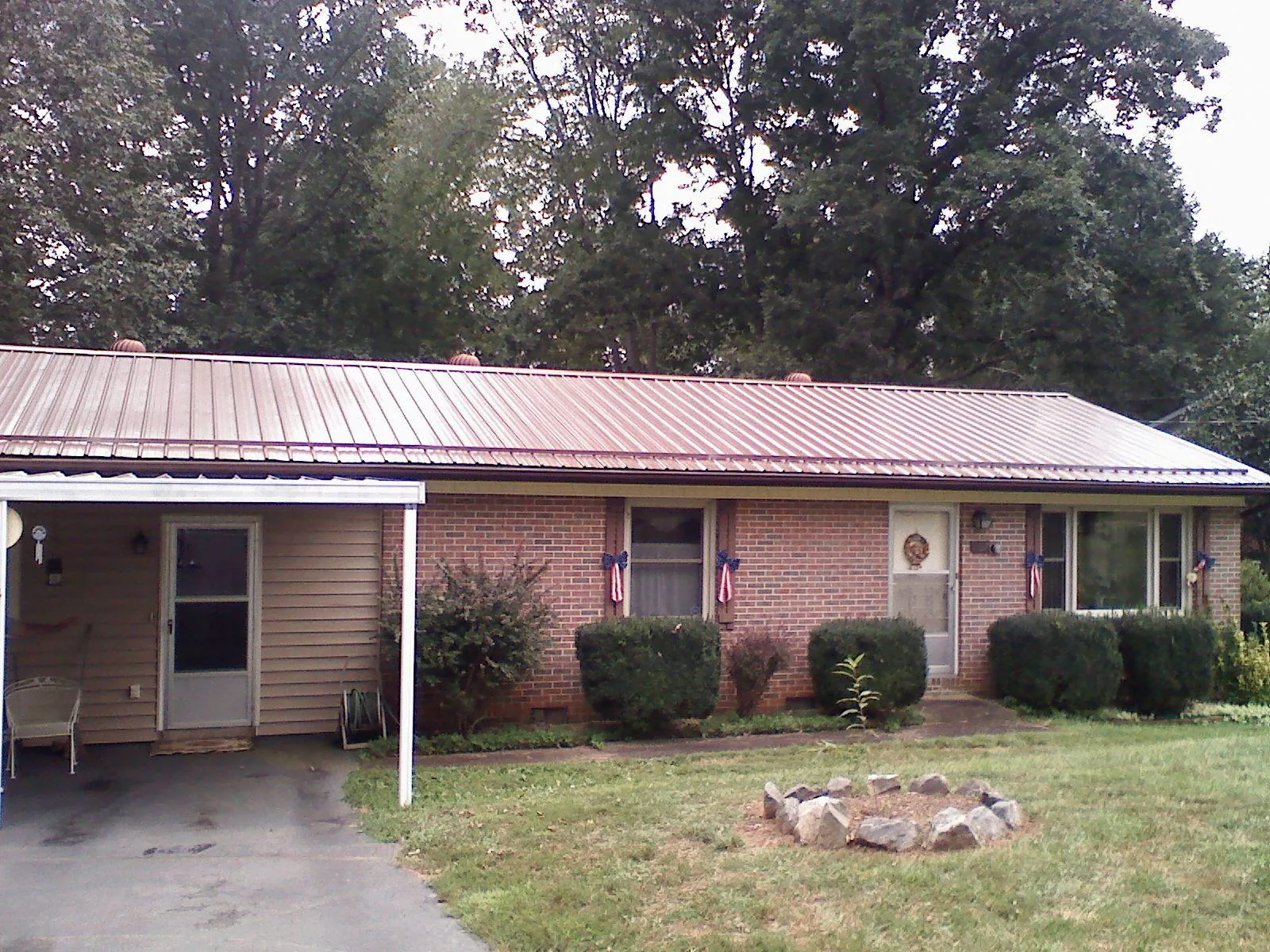 Bronze metal roof and carport on a brick ranch home — Roof Repair work by our crew in Derry